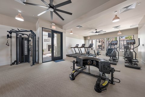 A gym with a variety of equipment including treadmills, weights, and a rowing machine.